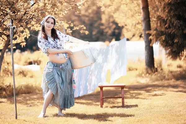 Pregnant woman hanging sheets on the rope for drying — Stock Photo, Image