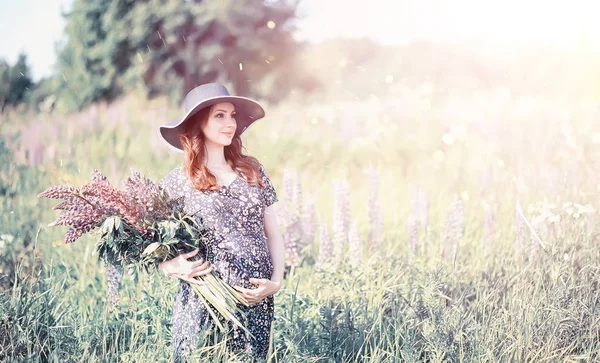 Ragazza incinta in un campo con fiori — Foto Stock