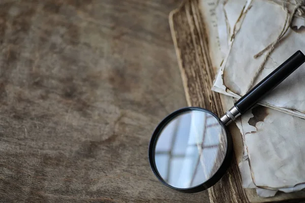 Old books on a wooden table and magnifier — Stock Photo, Image