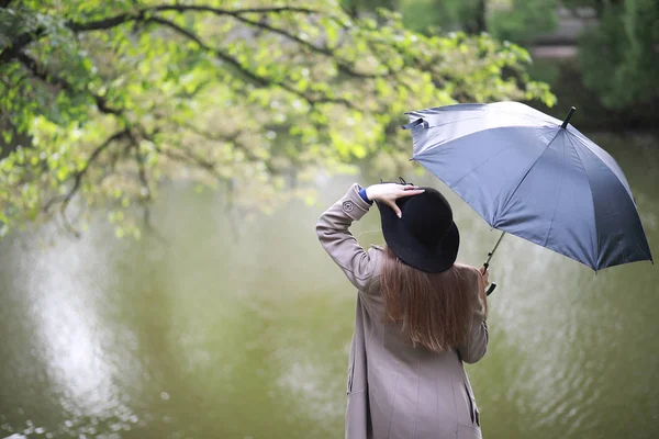 Chica joven en un abrigo en un parque de primavera — Foto de Stock