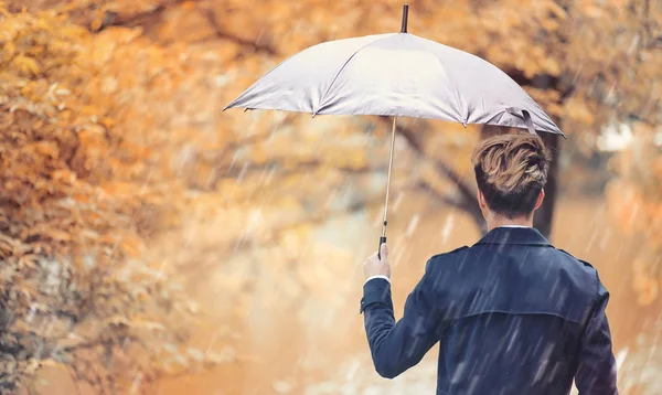 Musim gugur cuaca hujan dan seorang pemuda dengan payung — Stok Foto