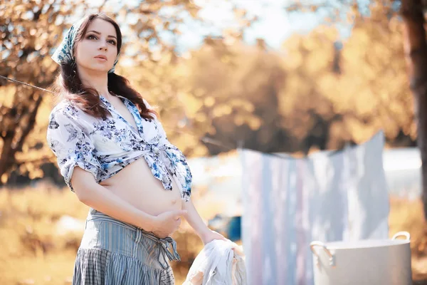 Kobieta w ciąży wiszące arkusze na linie do suszenia — Zdjęcie stockowe