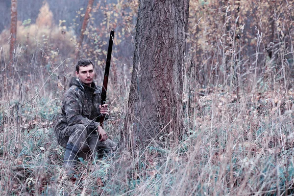 Un hombre en camuflaje y con un rifle de caza en un bosque en una sp —  Fotos de Stock