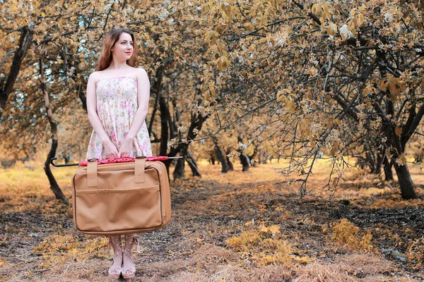 Niña con maleta de cuero para viajar en el parque de otoño a pie — Foto de Stock