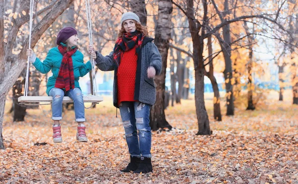 Дівчинка в осінньому міському парку в листопаді. Молода красива мати wi — стокове фото