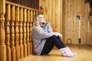 Genç bir kız kazakla merdivende oturuyor.