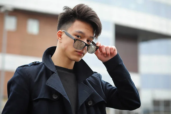 Asian young man in a coat on the street — Stock Photo, Image