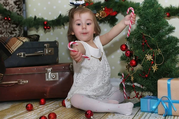 Menina sentada na frente de uma árvore de Natal — Fotografia de Stock