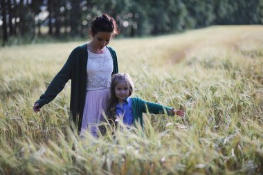 Genç anne yürüyerek buğday alanları içerisinde