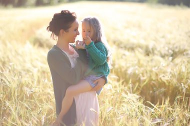 Genç anne yürüyerek buğday alanları içerisinde