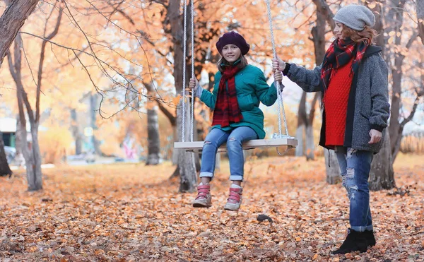 Chica en otoño parque de la ciudad en otoño de hojas. Joven hermosa madre wi — Foto de Stock