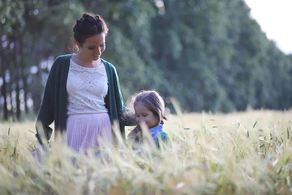 Молода мати ходить по полях пшениці — стокове фото