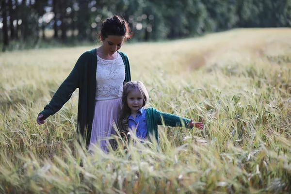 Genç anne yürüyerek buğday alanları içerisinde