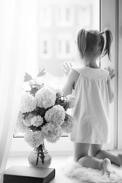 Uma menina está sentada no parapeito da janela. Um buquê de flores — Fotografia de Stock