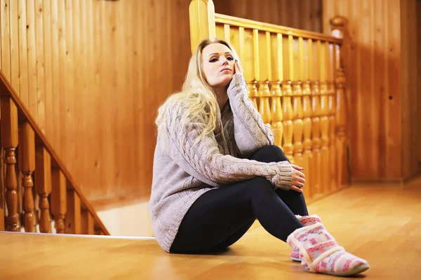 Uma jovem se senta em uma escada com uma camisola — Fotografia de Stock