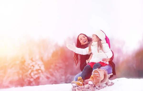 Zimowa bajka, młoda matka i jej córka jeździć na sankach — Zdjęcie stockowe