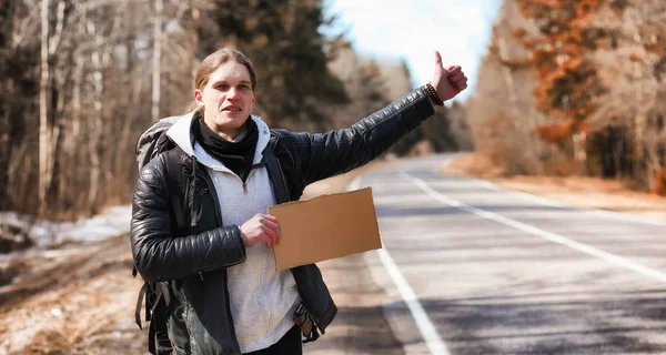 Un joven está haciendo autostop por todo el país. El hombre lo está intentando —  Fotos de Stock