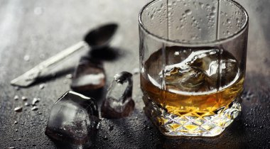 Bir cam ile buzlu viski. Küpleri buz ahşap bir masa üzerinde bir