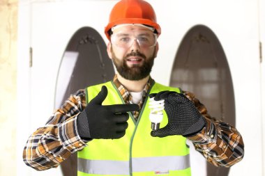 Kasklı adam elinde ampul tutuyor.