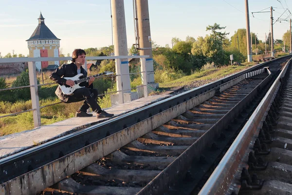 Homem com uma guitarra elétrica na paisagem industrial ao ar livre — Fotografia de Stock