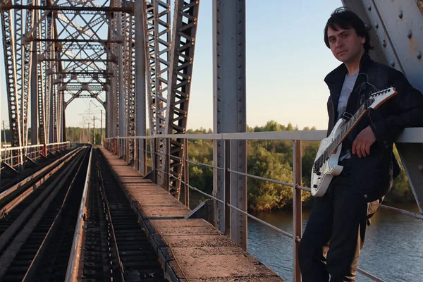 Homem com uma guitarra elétrica na paisagem industrial ao ar livre — Fotografia de Stock