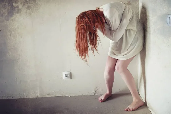 Uma rapariga com cabelo ruivo numa camisa. Violência doméstica e sacrifício. Menina com uma psique doente . — Fotografia de Stock