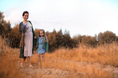 Anne ve kızı yolda yürüyor.