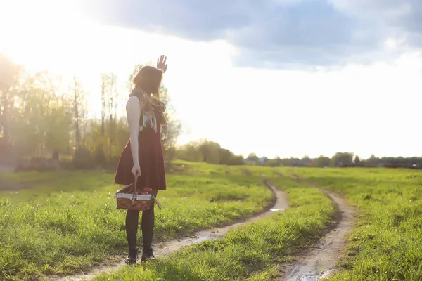 Una ragazza con un cappello mentre passeggia nel parco. Una ragazza con un cesto a piedi — Foto Stock