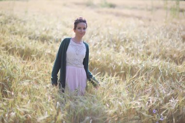 Genç anne yürüyerek buğday alanları içerisinde