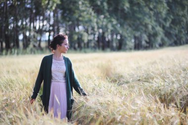 Genç anne yürüyerek buğday alanları içerisinde