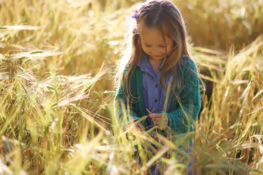 Genç anne yürüyerek buğday alanları içerisinde