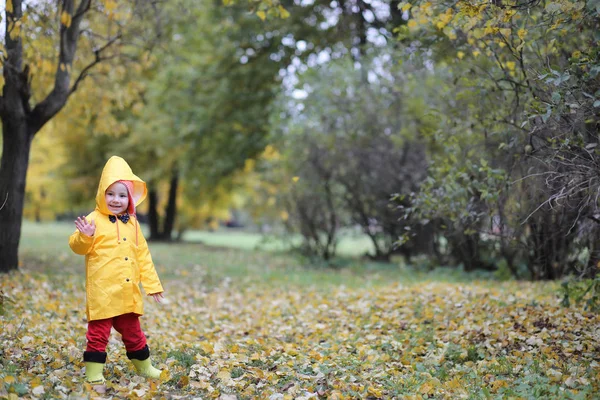 Ett barn i en regnrock för en promenad utanför — Stockfoto