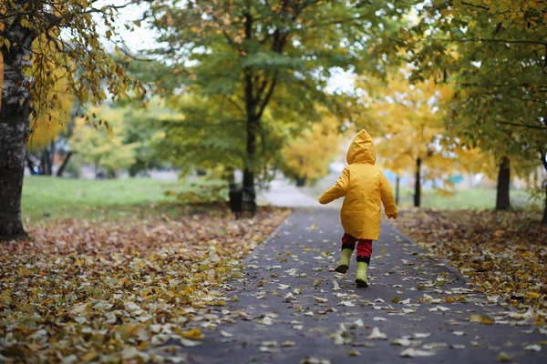 Ett barn i en regnrock för en promenad utanför — Stockfoto