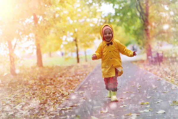 Ett barn i en regnrock en promenad utanför i höst — Stockfoto