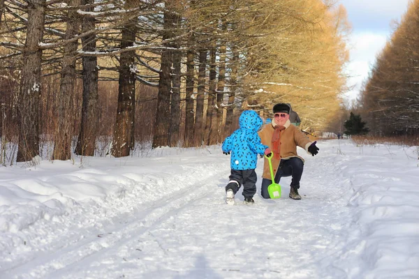 Niño corriendo en el parque de invierno y divertirse con la familia — Foto de Stock