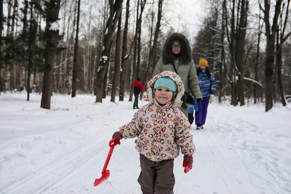 Niño corriendo en el parque de invierno y divertirse con la familia — Foto de Stock