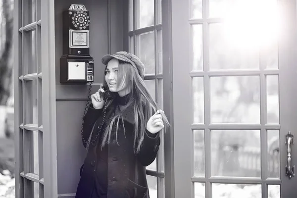 Piękna młoda dziewczyna w budce telefonicznej. Dziewczyna rozmawia na th — Zdjęcie stockowe