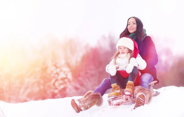 En vintersaga, en ung mamma och hennes dotter rida en släde — Stockfoto