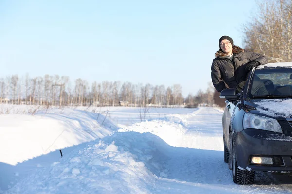 Man looks out the car window at the snow-covered road — Stock Photo, Image