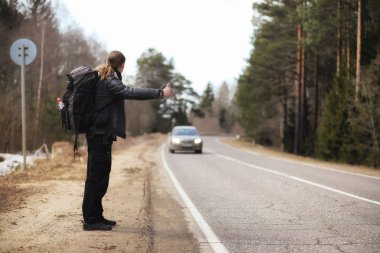 Genç bir adam ülke çapında otostop. Adam çalışıyor