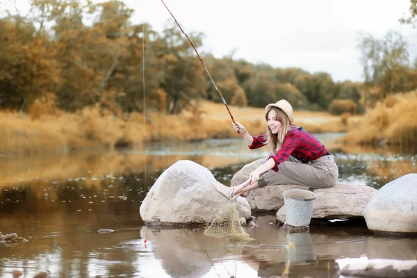 Flicka i höst med ett fiskespö — Stockfoto