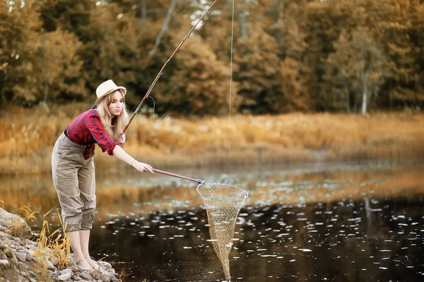 Girl in autumn with a fishing rod — Stock Photo, Image