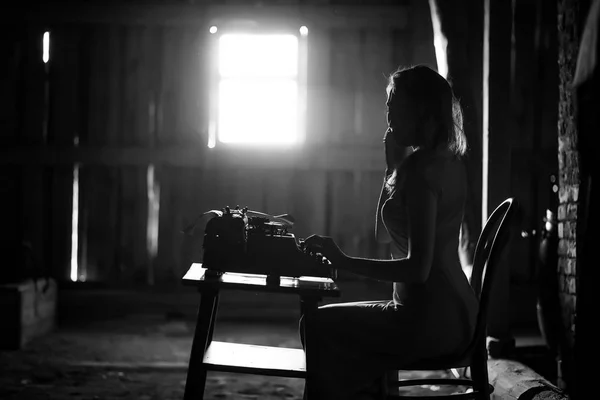 A girl prints on an old typewriter — Stock Photo, Image