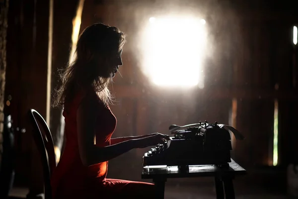 Una ragazza in stile retrò stampa su una vecchia macchina da scrivere — Foto Stock