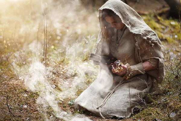 A man in a cassock spends a ritual in a dark forest — Stock Photo, Image