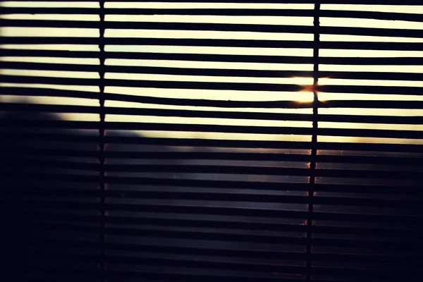 O sol está brilhando através das cortinas de madeira — Fotografia de Stock