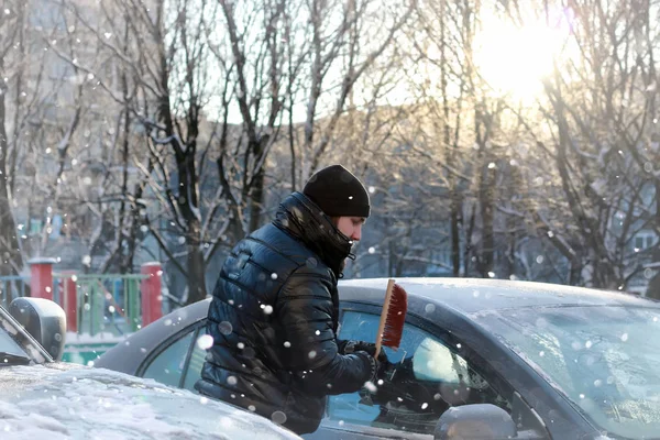 Man cleans snow from the glass at the car — Stock Photo, Image