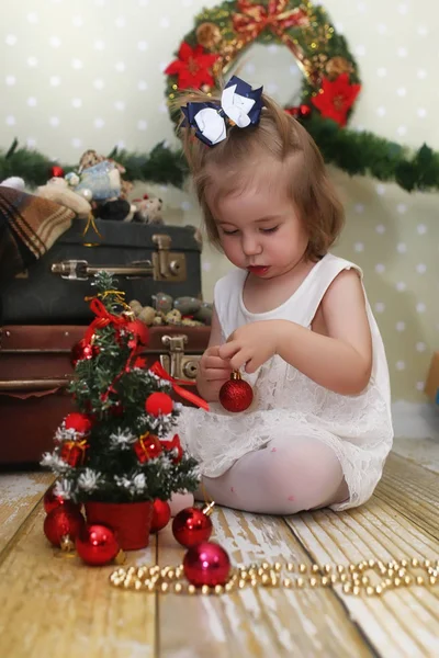 Menina sentada na frente de uma árvore de Natal — Fotografia de Stock