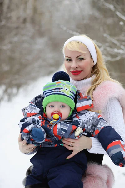 Mladá maminka chodí na zimní den s dítětem v náručí v th — Stock fotografie