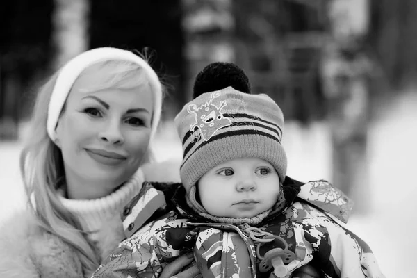 Молода мама гуляє в зимовий день з дитиною на руках — стокове фото